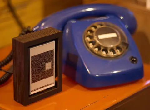 The object standing next to an old, blue rotary phone.