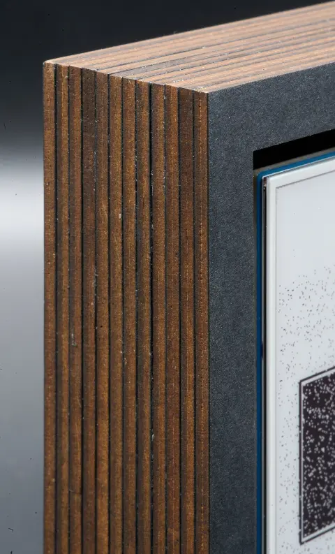A closeup of the left side of the object. The layers of brown cardboard with the thin slices of black paper between them, can be clearly seen.