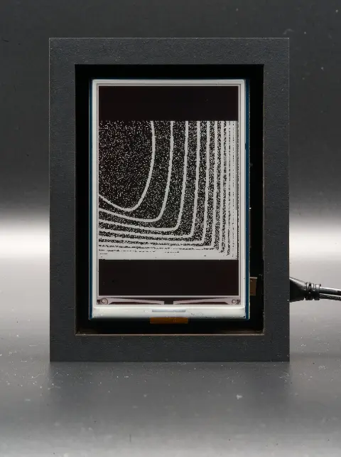 The object from the front. On its display there are contrasting white lines on a black background. The lines morph into a blob.