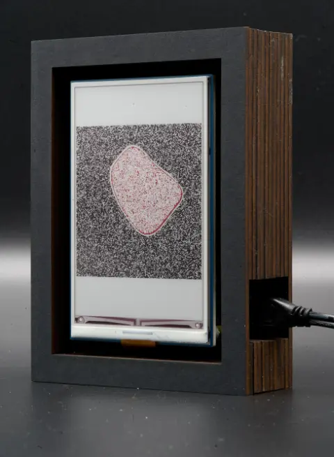 The object, showing a light red blob on a dark grey background on its screen.