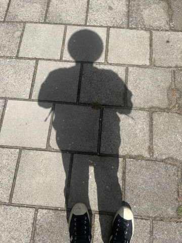 The shadow of a person with a remarkably circular head. There’s a working clock in this circular head.