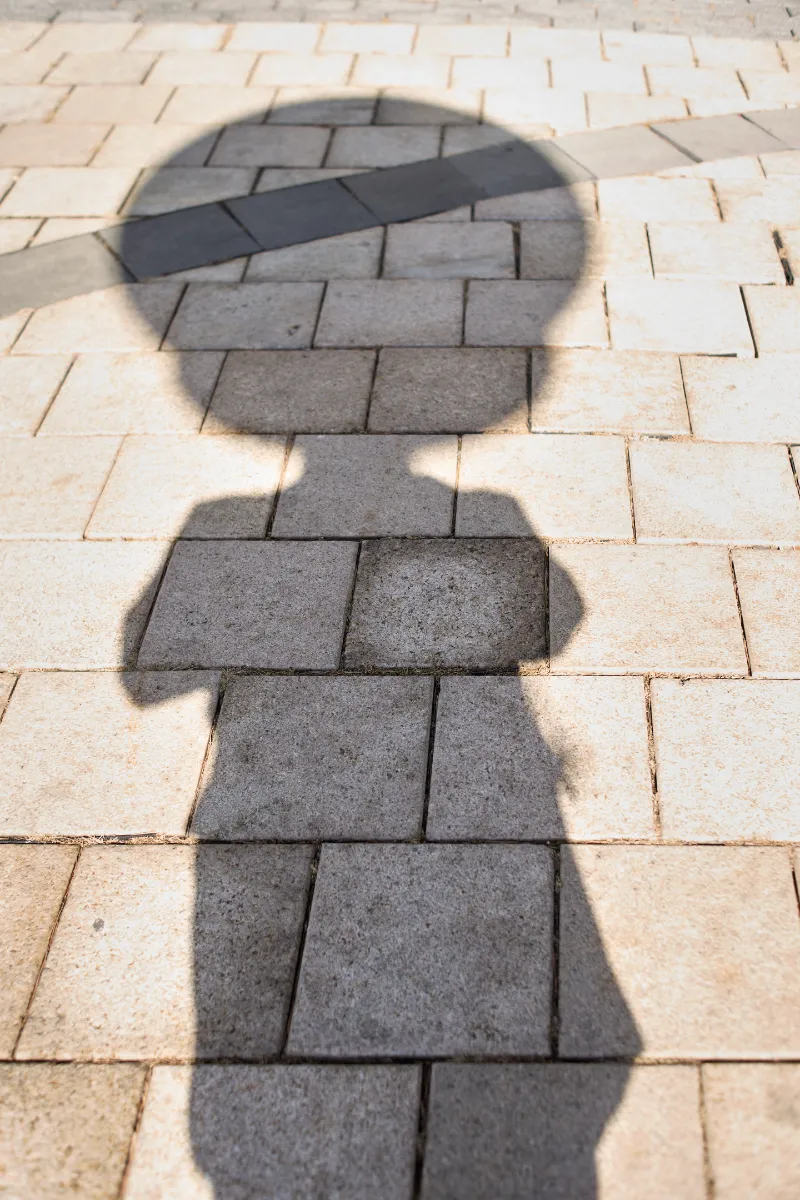 The shadow of a person with a remarkably circular head. There’s a working clock in this circular head.