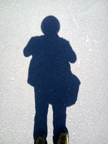 The shadow of a person with a remarkably circular, and remarkably large head. There’s a working clock in this circular head.