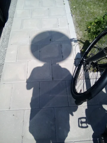 The shadow of a person with a remarkably circular, and remarkably large head. There’s a working clock in this circular head.