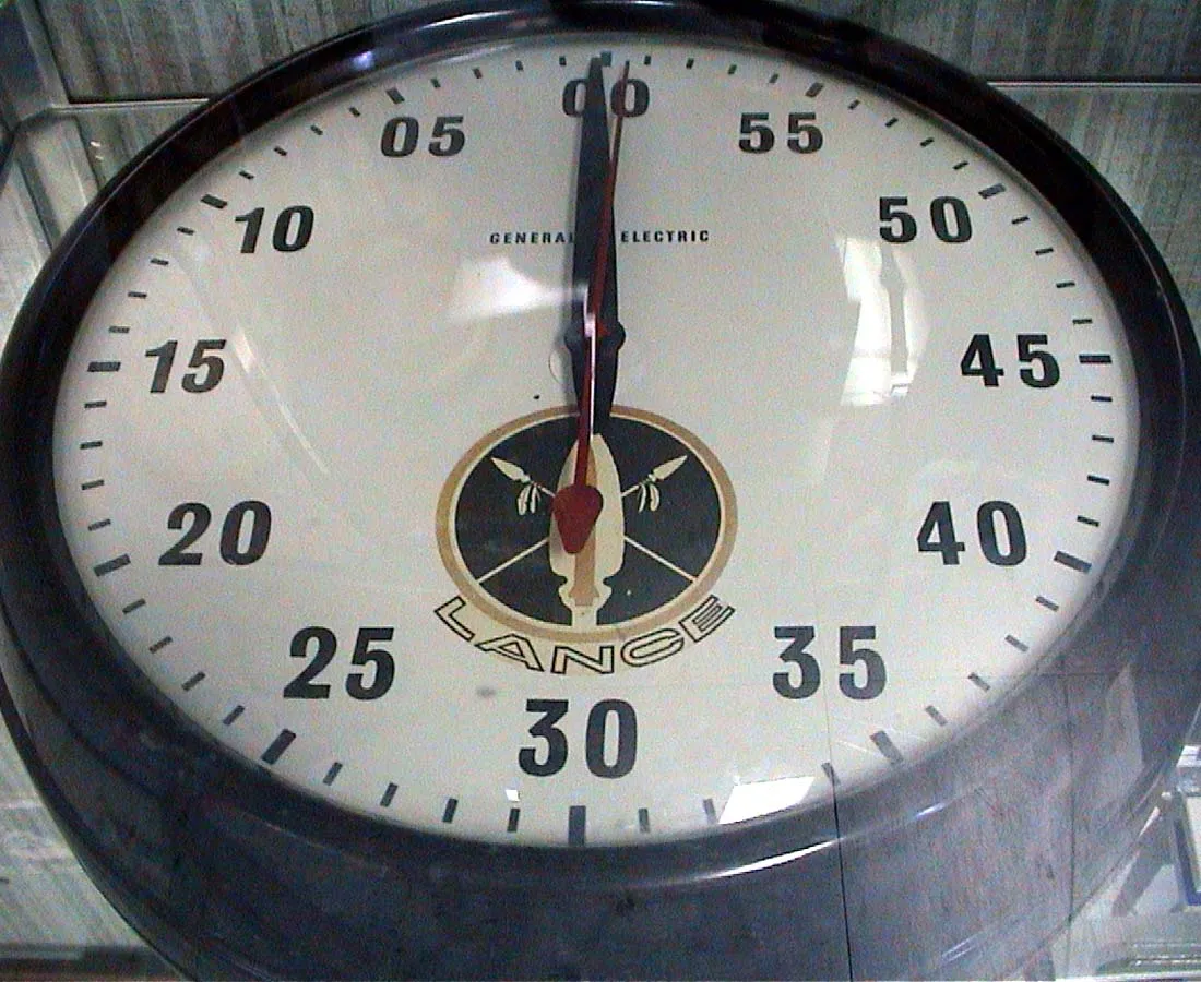 A large, fullscreen clock. Both arms point up, it is exactly twelve o’clock.