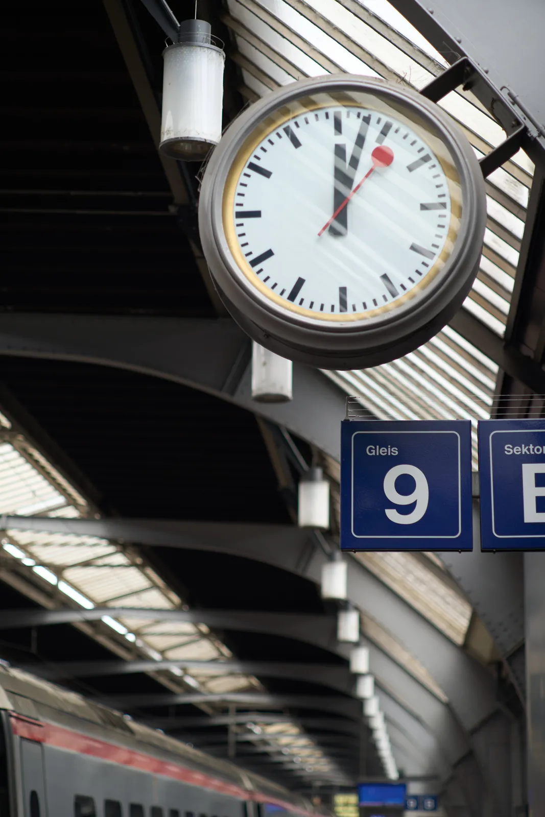 A swiss clock on platform 9 on a train station in Switzerland. It points at 3 minutes past 12.