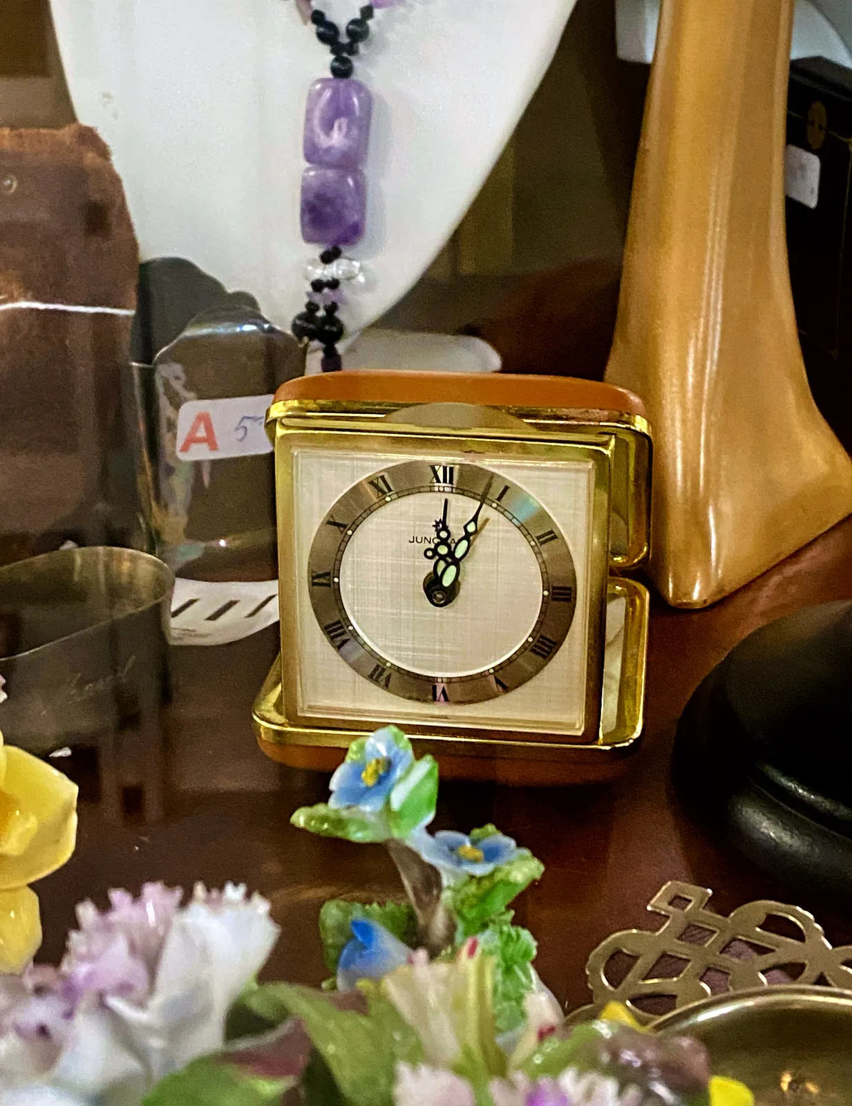 A travel clock in a thrift shop. It points at 4 minutes past 12.
