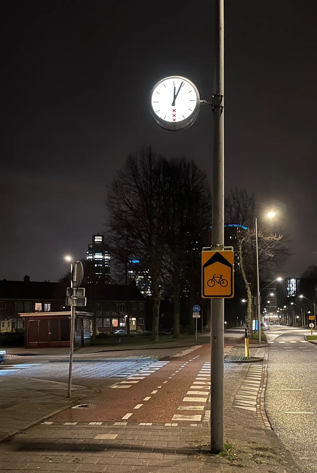 A clock on a pole points at 4 minutes after midnight.