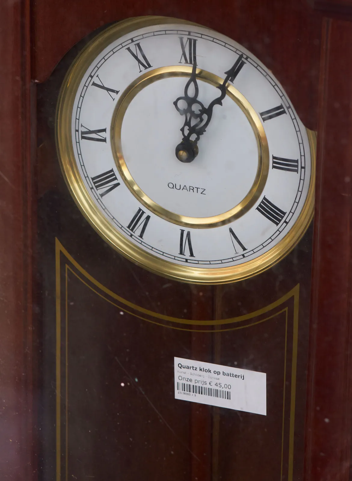 A clock that looks older than it is, since it is a quartz clock (it uses batteries, it says on the sticker). It points at five minutes past twelve.