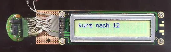 A digital device says it is Kurz nach 12, which means Shortly after twelve in German.