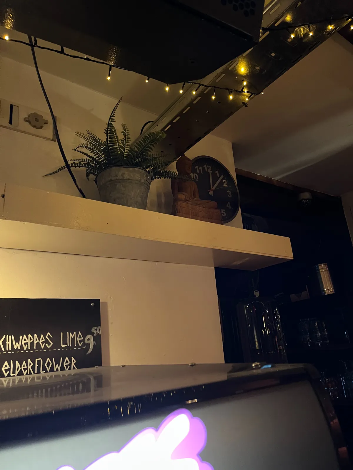 A clock in a bar points at 7 past 12.