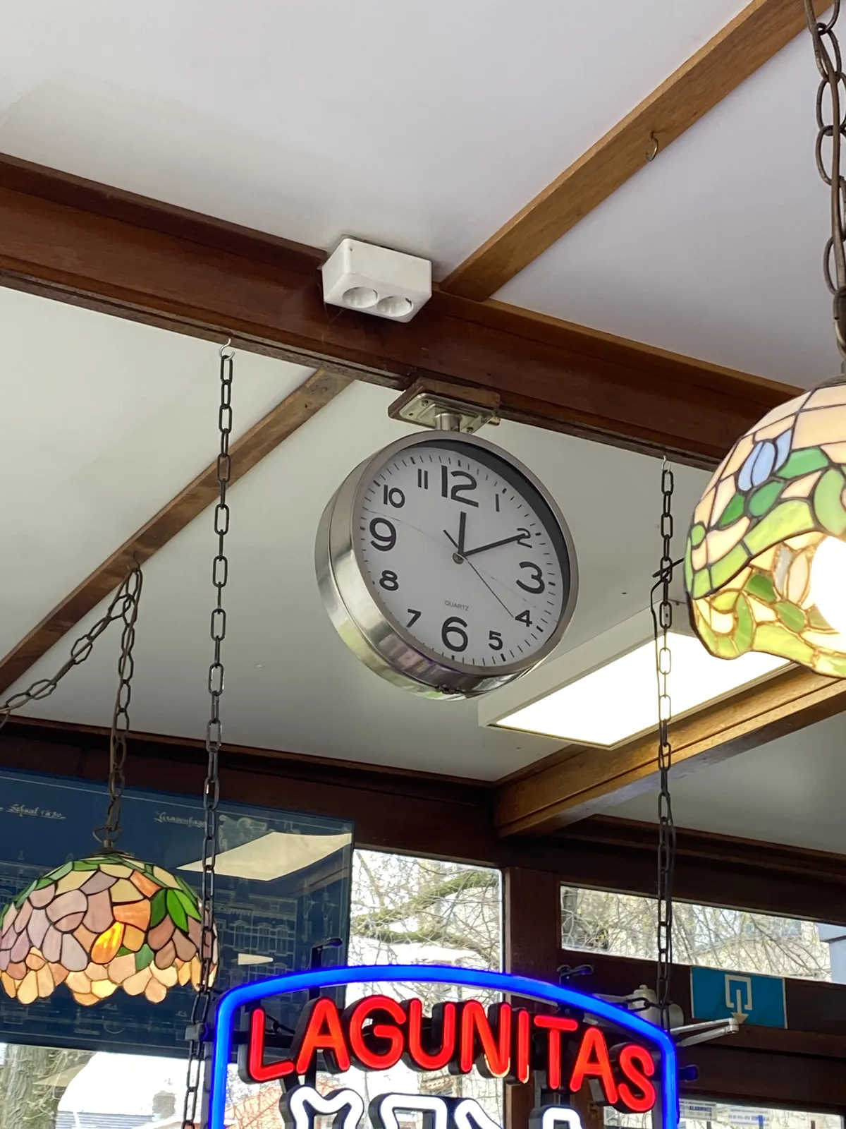 Some colourful lamps hanging from the ceiling. Also, a neon sign saying Lagunitas. And there’s a clock attached to the ceiling which points at 9 minutes past 12.