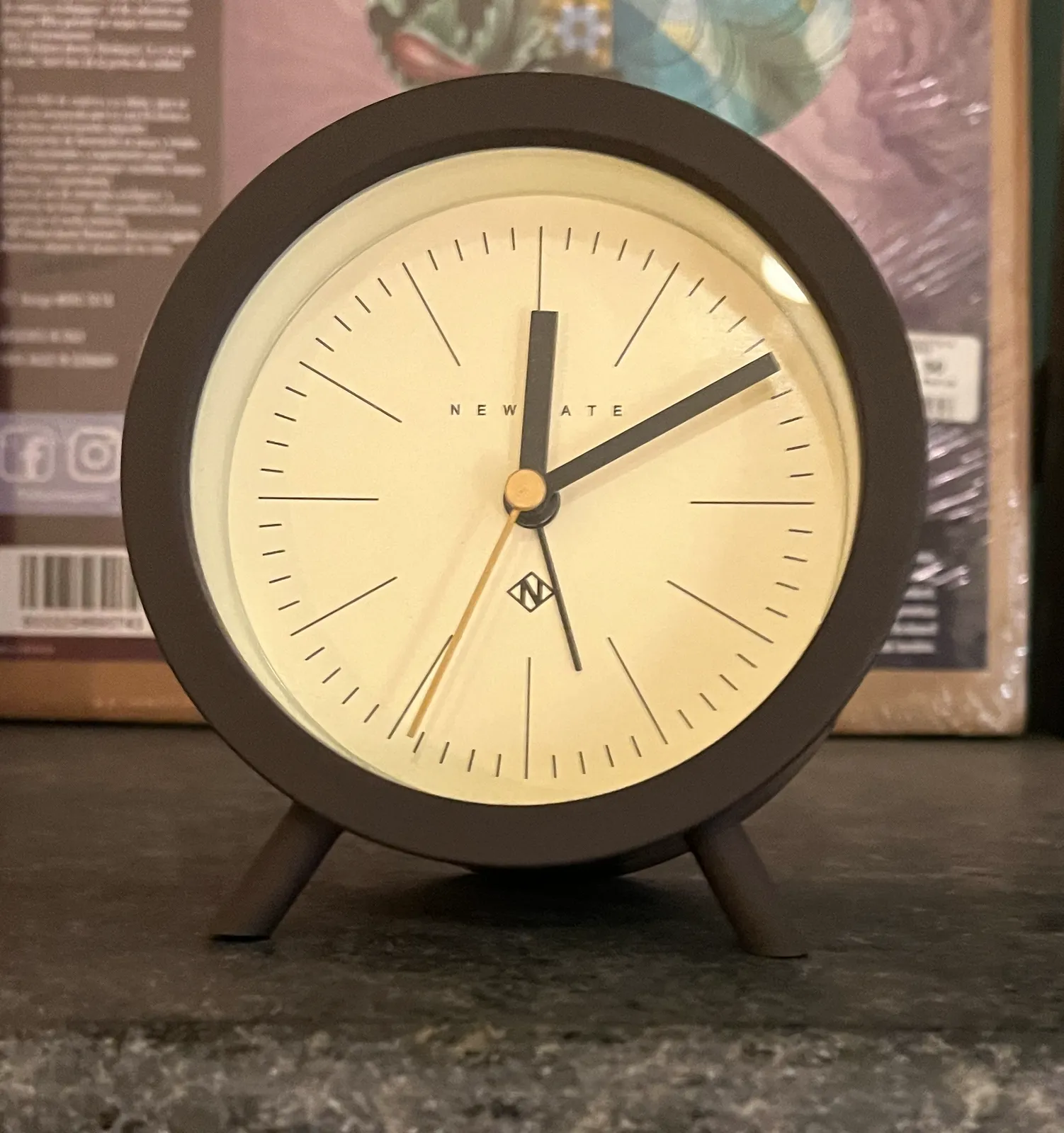 A closeup of a simple, small table clock. It points at 10 past twelve.