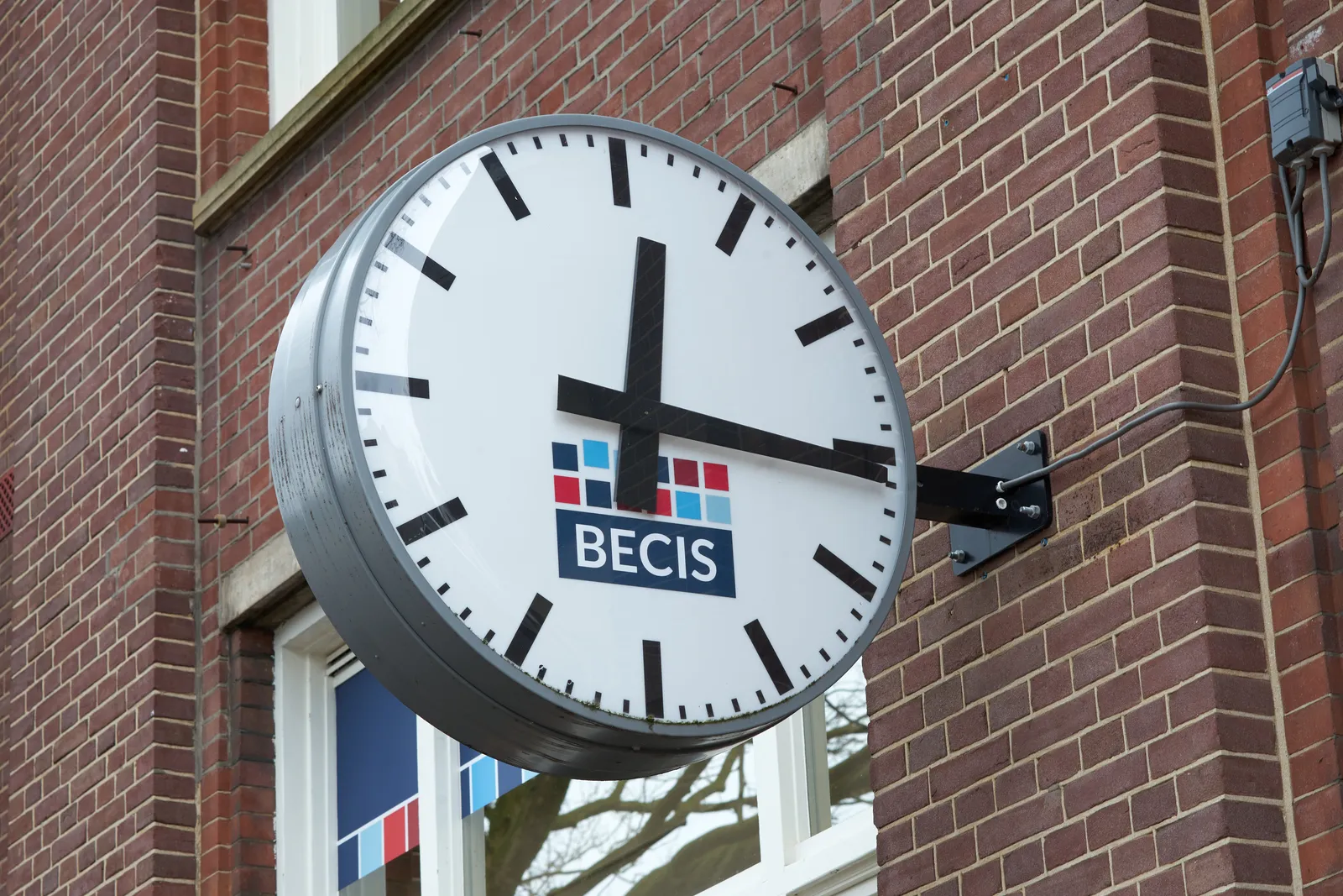 This clock, attached to a wall, points at 16 past 12. 