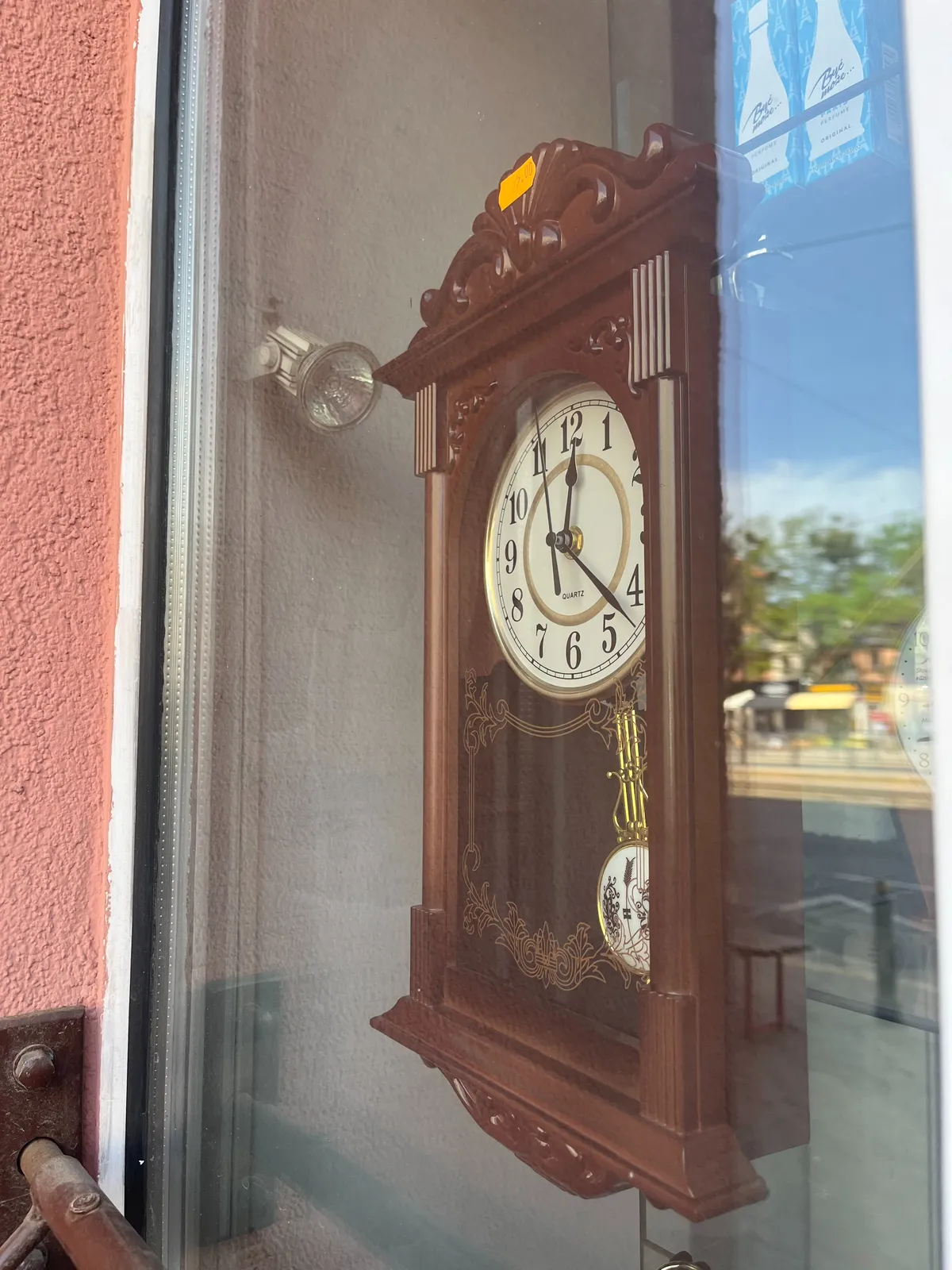 An old wooden clock in a shop window. It points at 22 minutes past twelve.