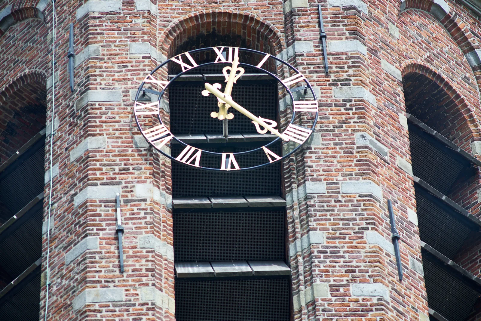 A detail of a church tower. The clock on the tower points at 22 past twelve.