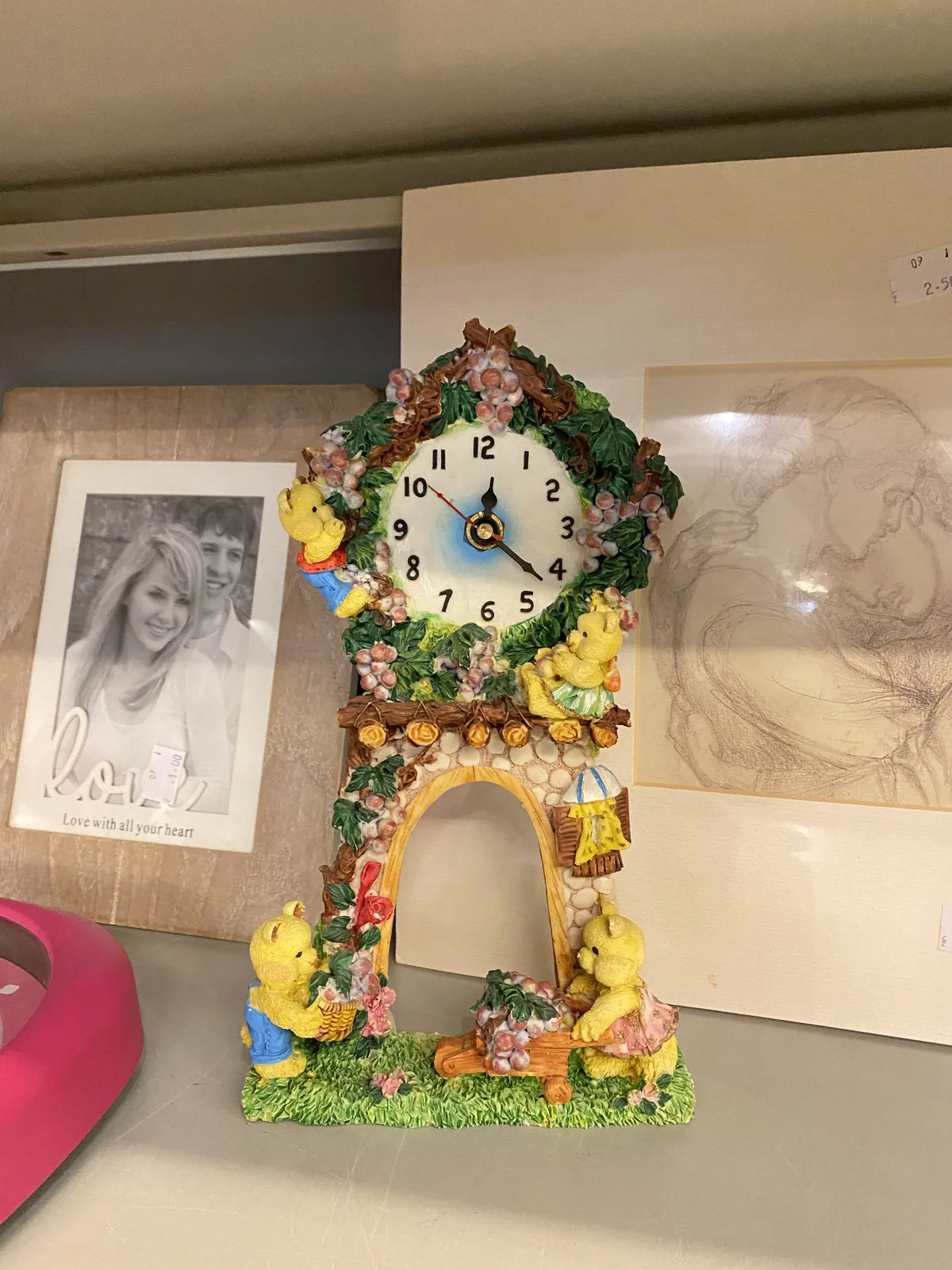 A strange colourful clock with some happy yellow bears climbing on it. The clock points at 22 minutes past 12.