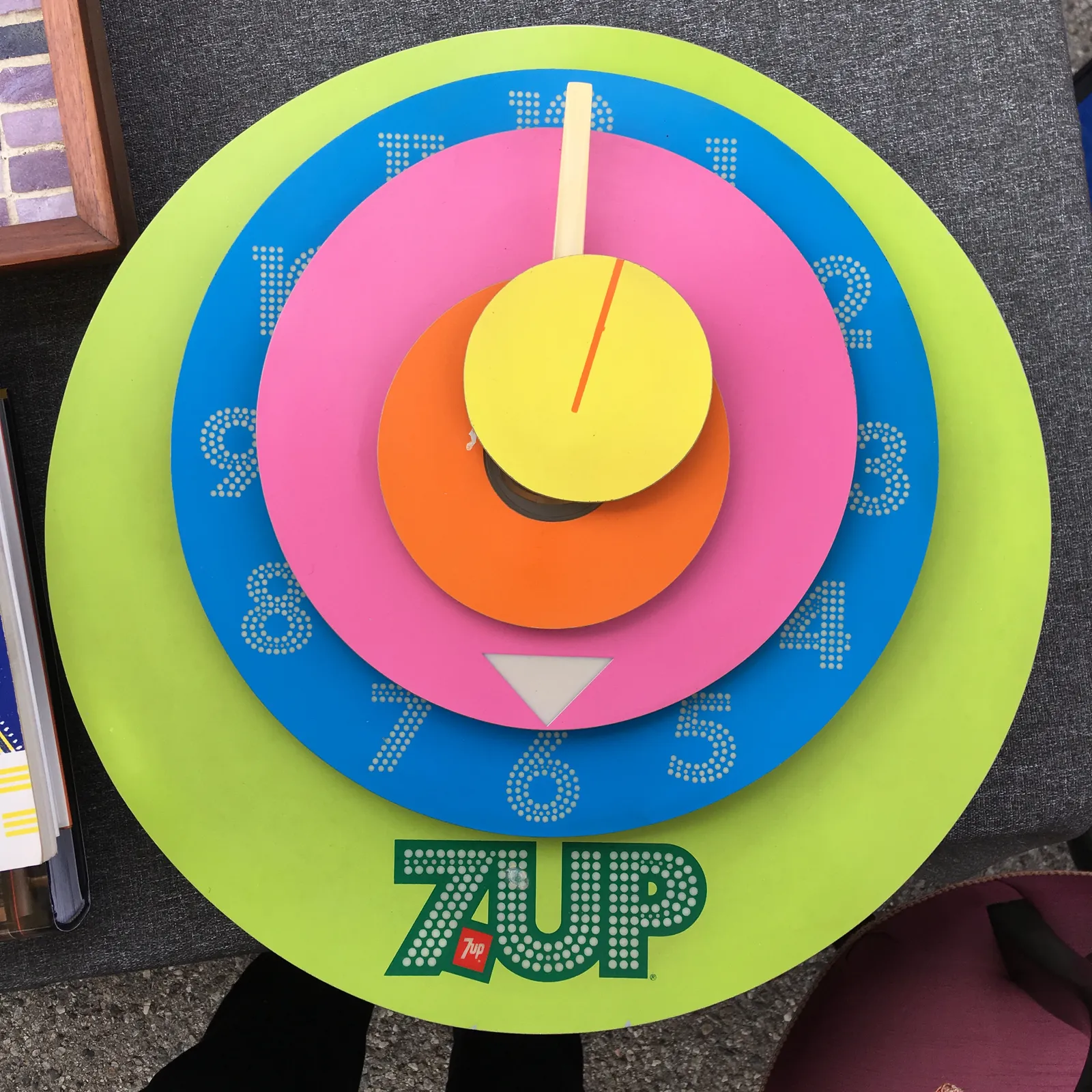 A very colourful, rather abstract clock, which is also a 7up advertisement. It consists of a few brightly coloured circles. Some of these circles have arrows on them, and these turn out to be the hands of the clock. Once you figure that out you can see that it is approximately half past 12.