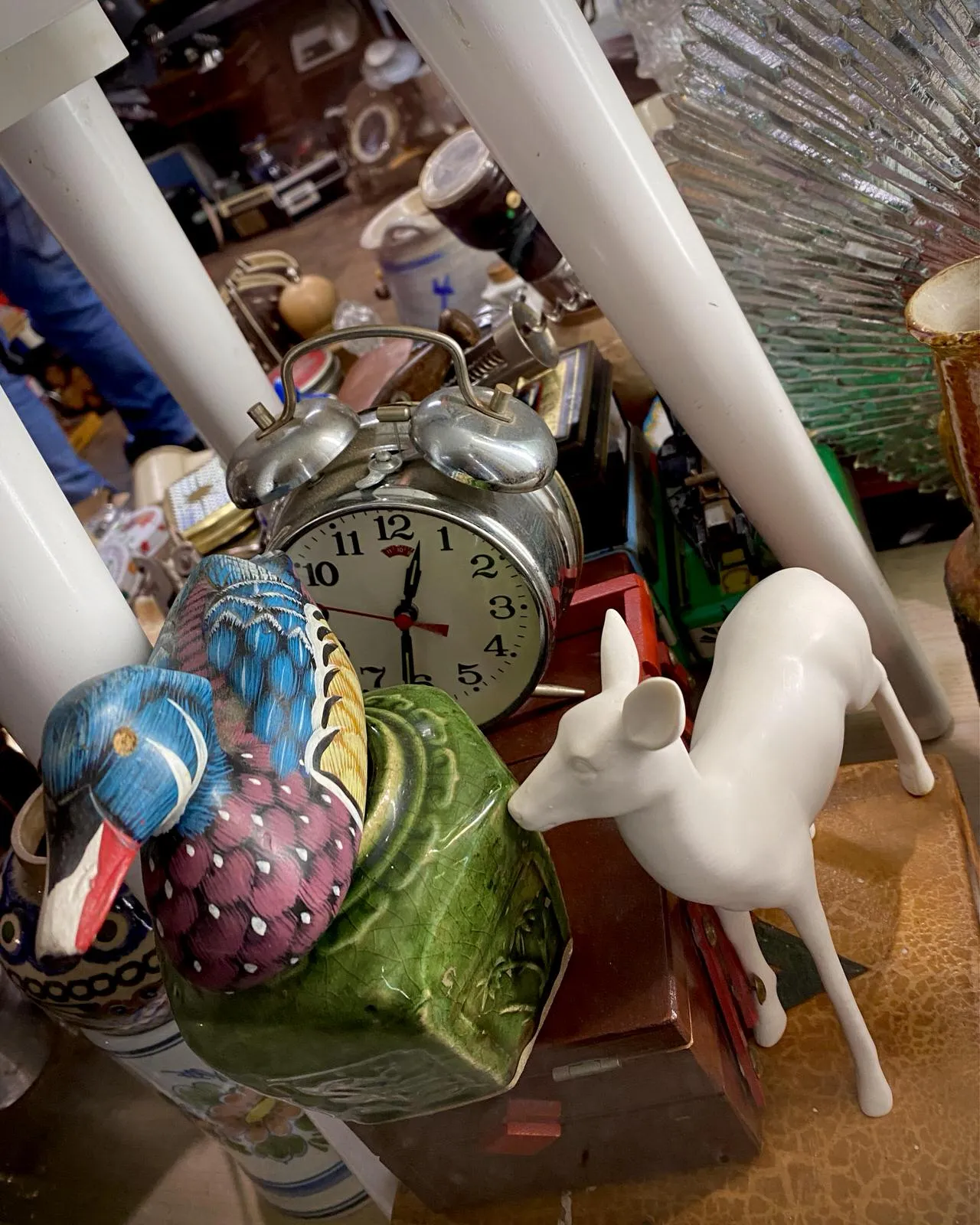 A picture in a thrift shop. There’s all kinds of stuff, and also a clock which points at 31 past 12.