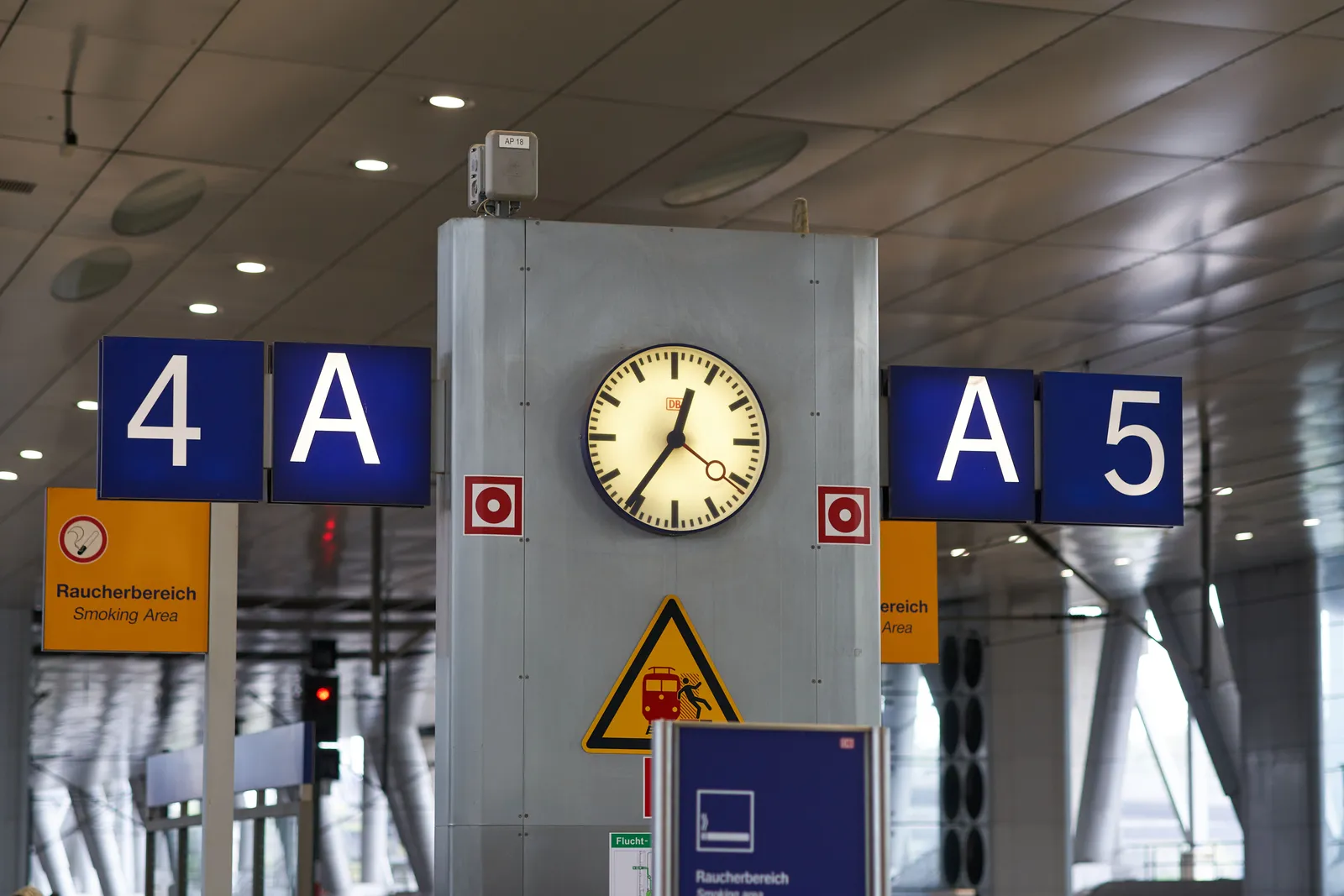A clock between platform number 4 and 5. It points at 24 minutes to 1.