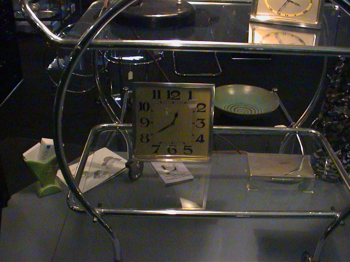A clock in a shop window points at twenty to one.