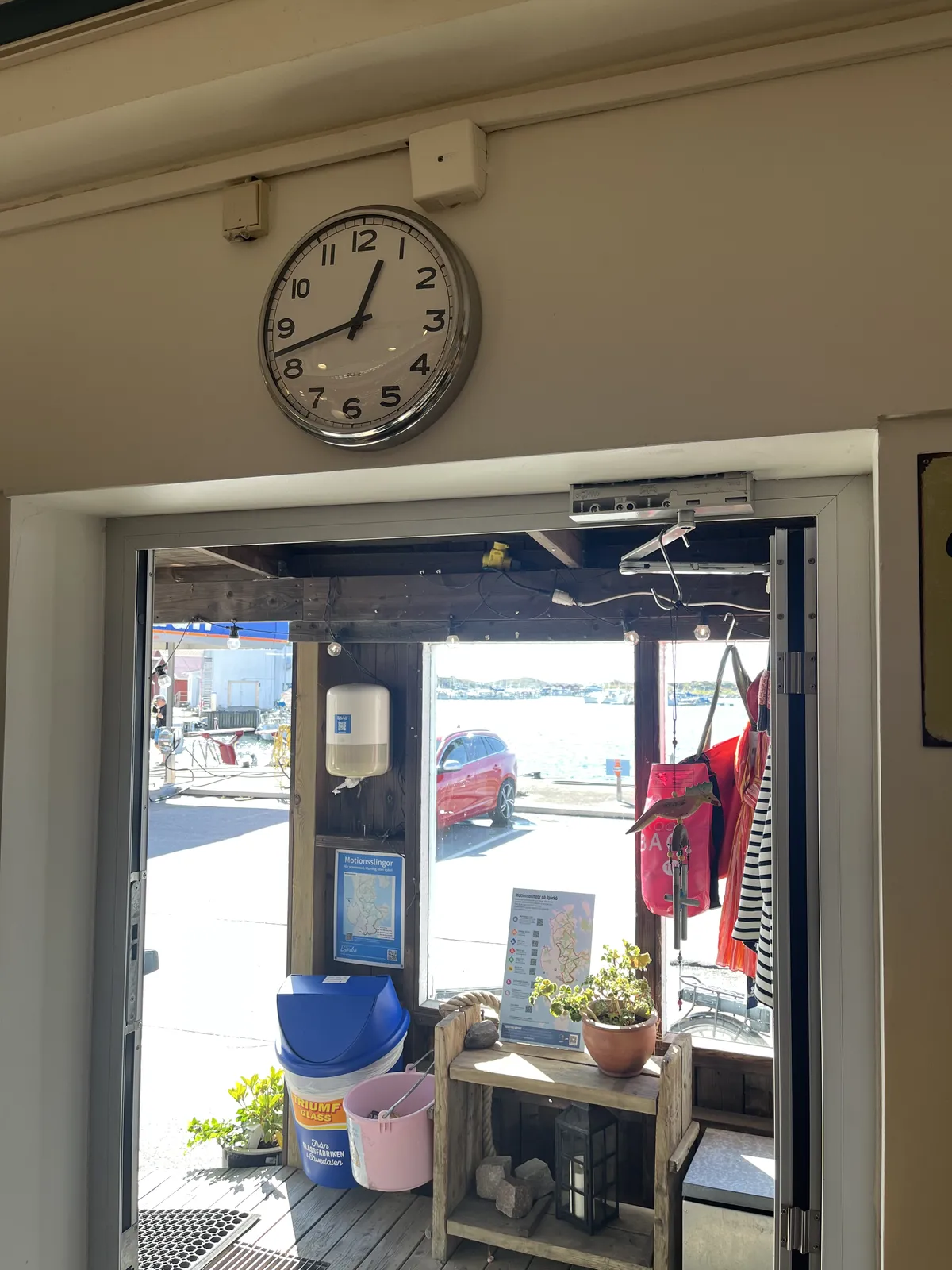 Looking out, through an open door. Above the door there’s a clock which points at 42 minutes past twelve.