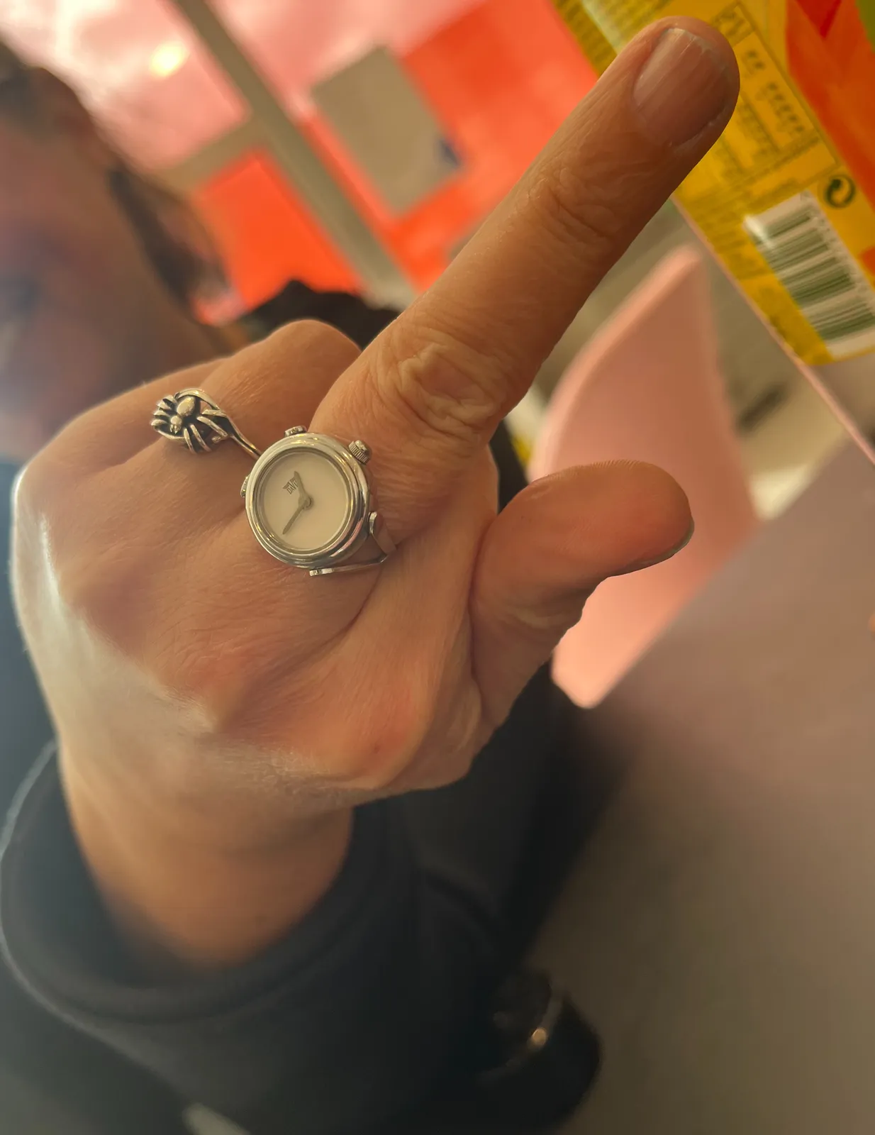 Someone is pointing their middle finger right at the lens. On this middle finger there’s a ring with a clock on it. It points at 16 minutes to one