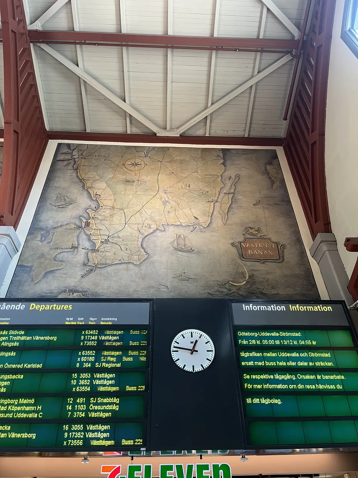 Below a huge old looking map, there are two large displays. The one on the left shows the departing train times, the one on the right shows information. Between these displays there’s a clock which points at 13 minutes to one