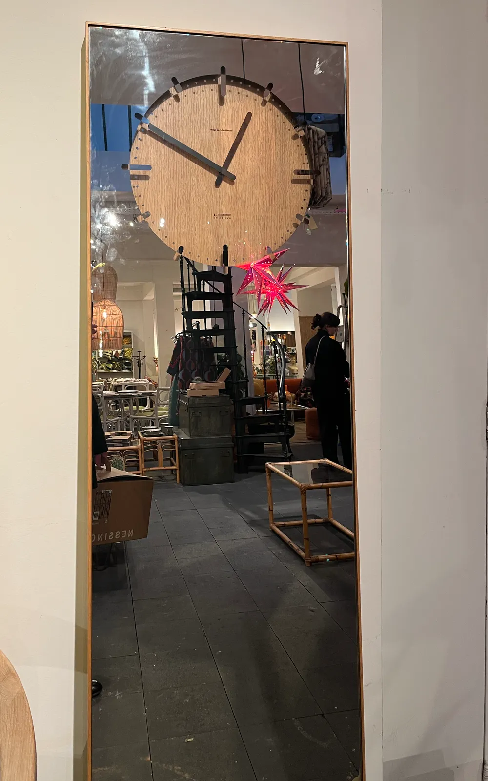 A clock is cut out from a large standing mirror. It points at 10 to one
