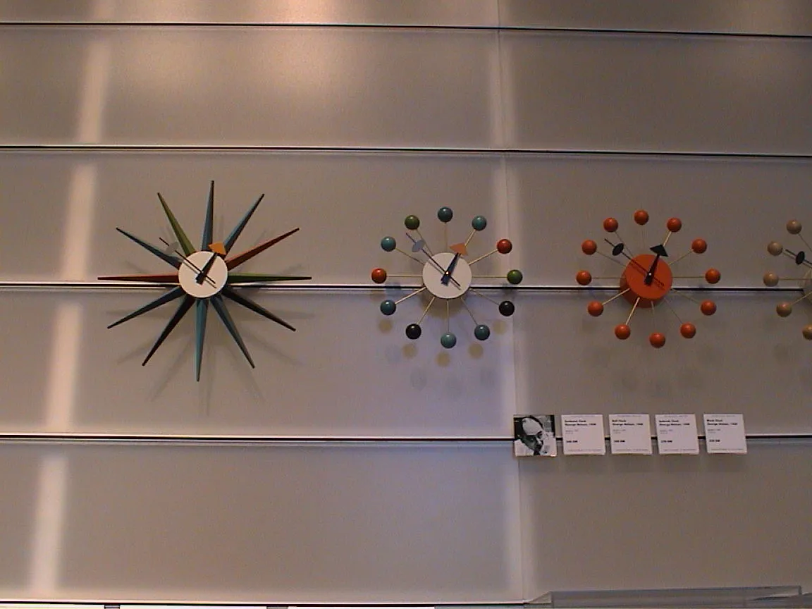Three novelty clocks on a wall, some with coloured dots, another with large spikes, show it is seven to one.