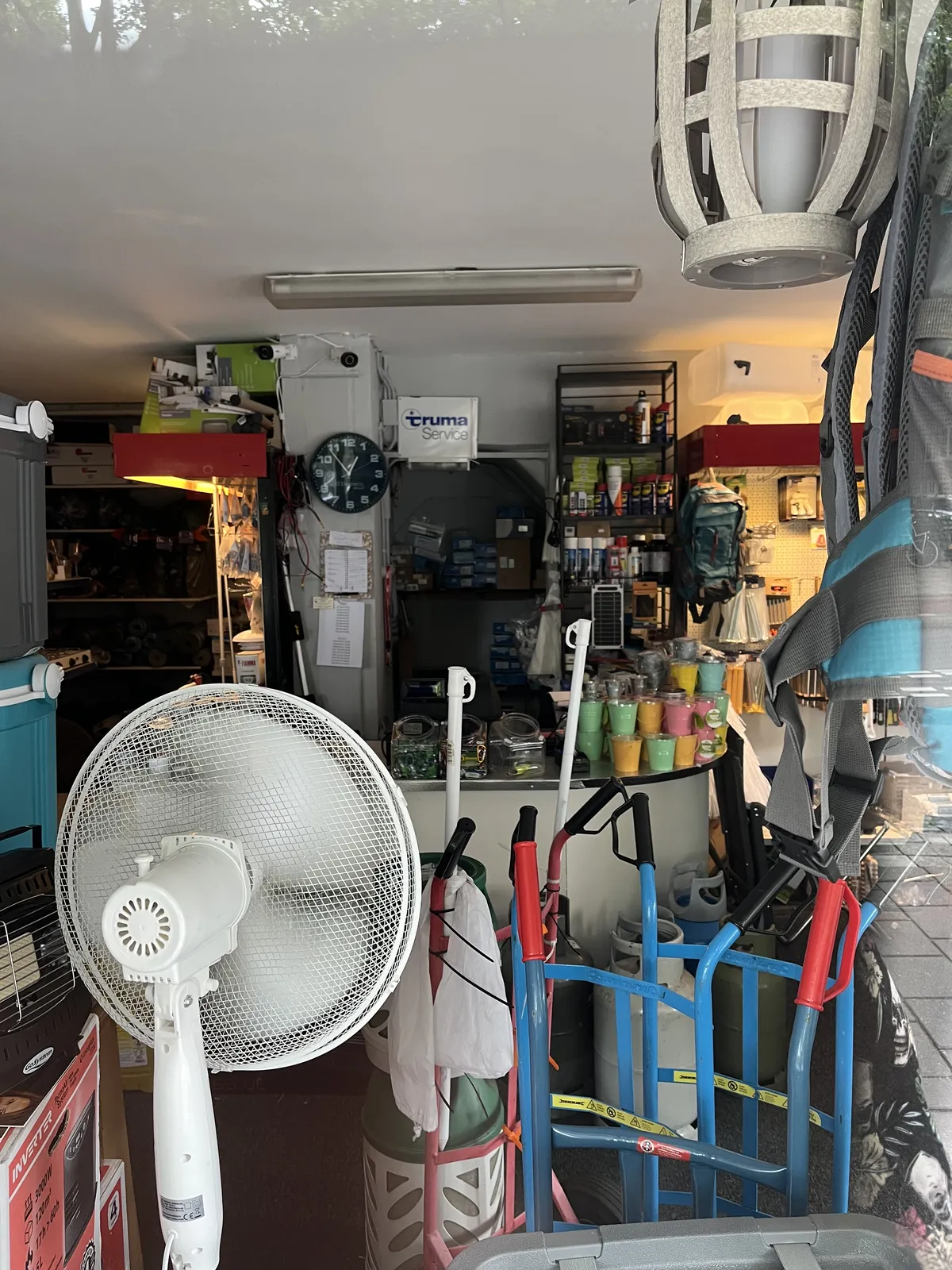 Peeking into a shop which sells all kinds of camping stuff, so it seems. On the wall there’s a clock. It points at seven minutes to one.