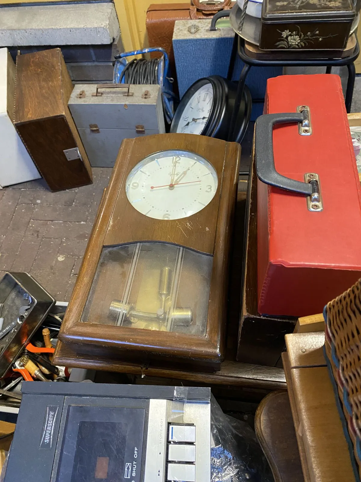 A picture in a thrift shop. There’s all kinds of stuff, and also a clock, laying on the ground, which points at exactly 1 o’clock.
