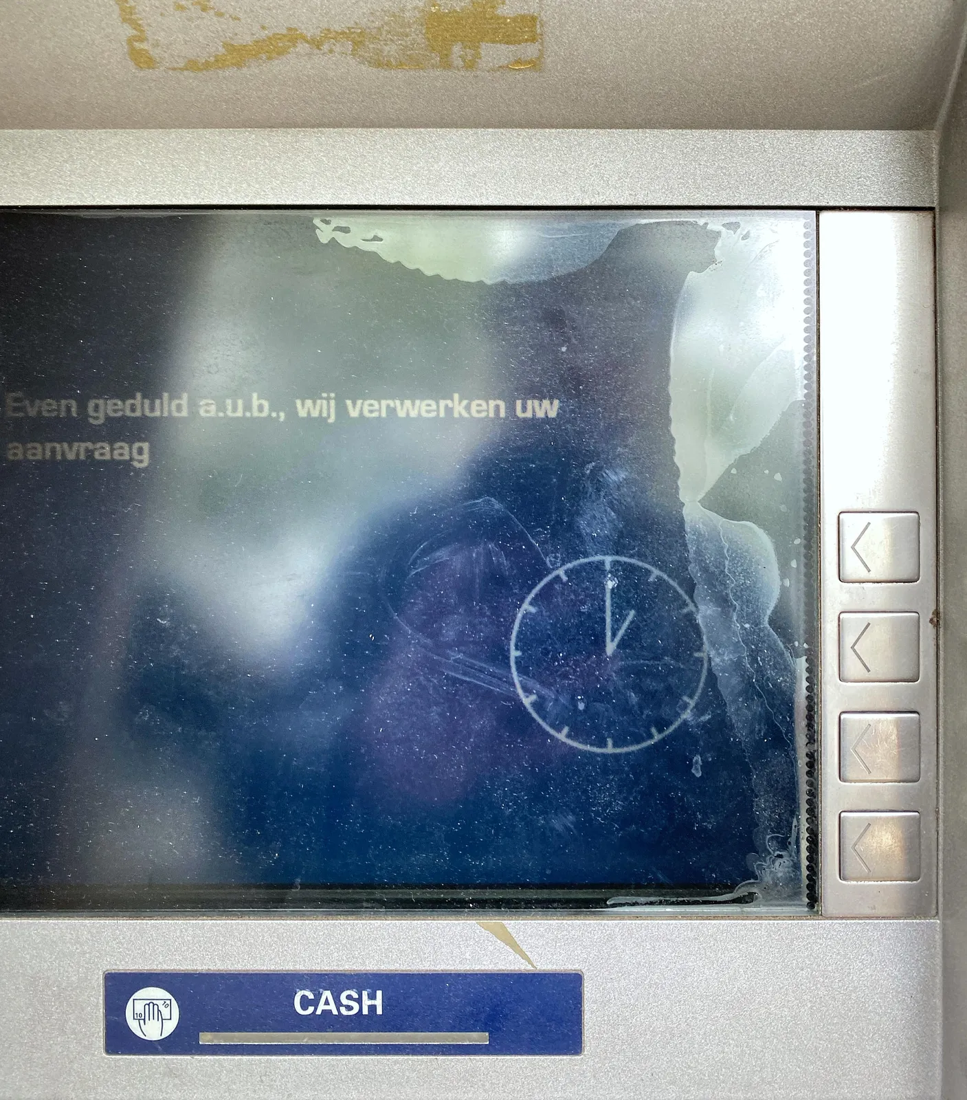 A clock on the display of an ATM. It points at one o’clock.