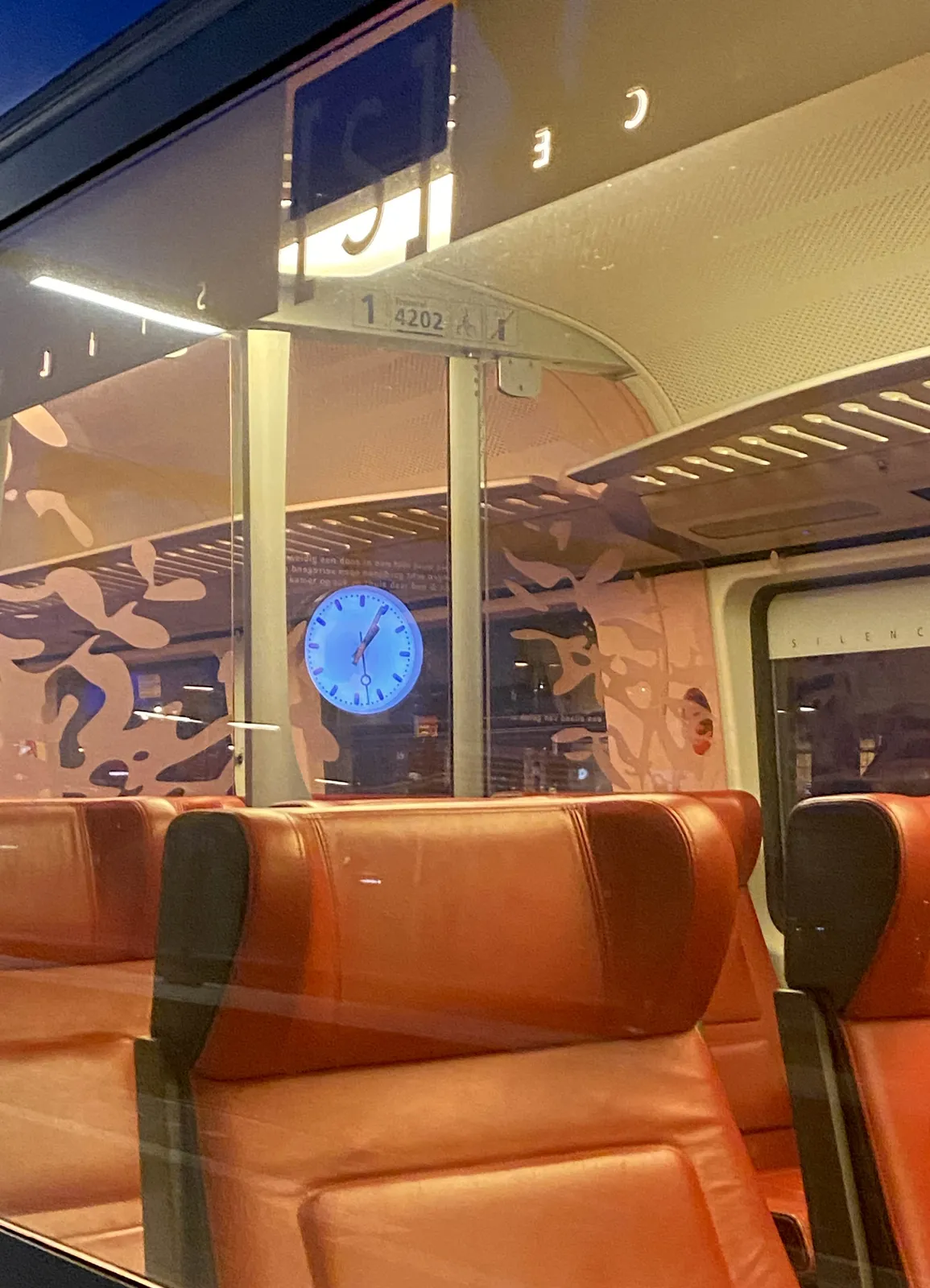 Somehow the reflection of a station clock can be seen inside an empty train. It’s a bit unclear how this reflection works exactly. The reflection of the clock seems to point at 4 minutes past one.
