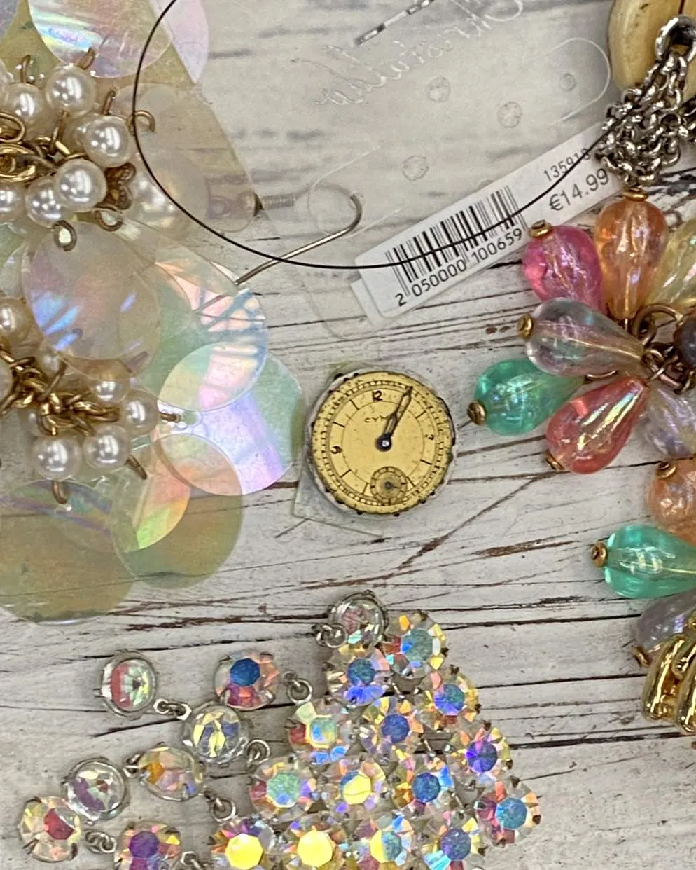 A small watch dropped between various stuff on a flea market. It points at 5 minutes past one.