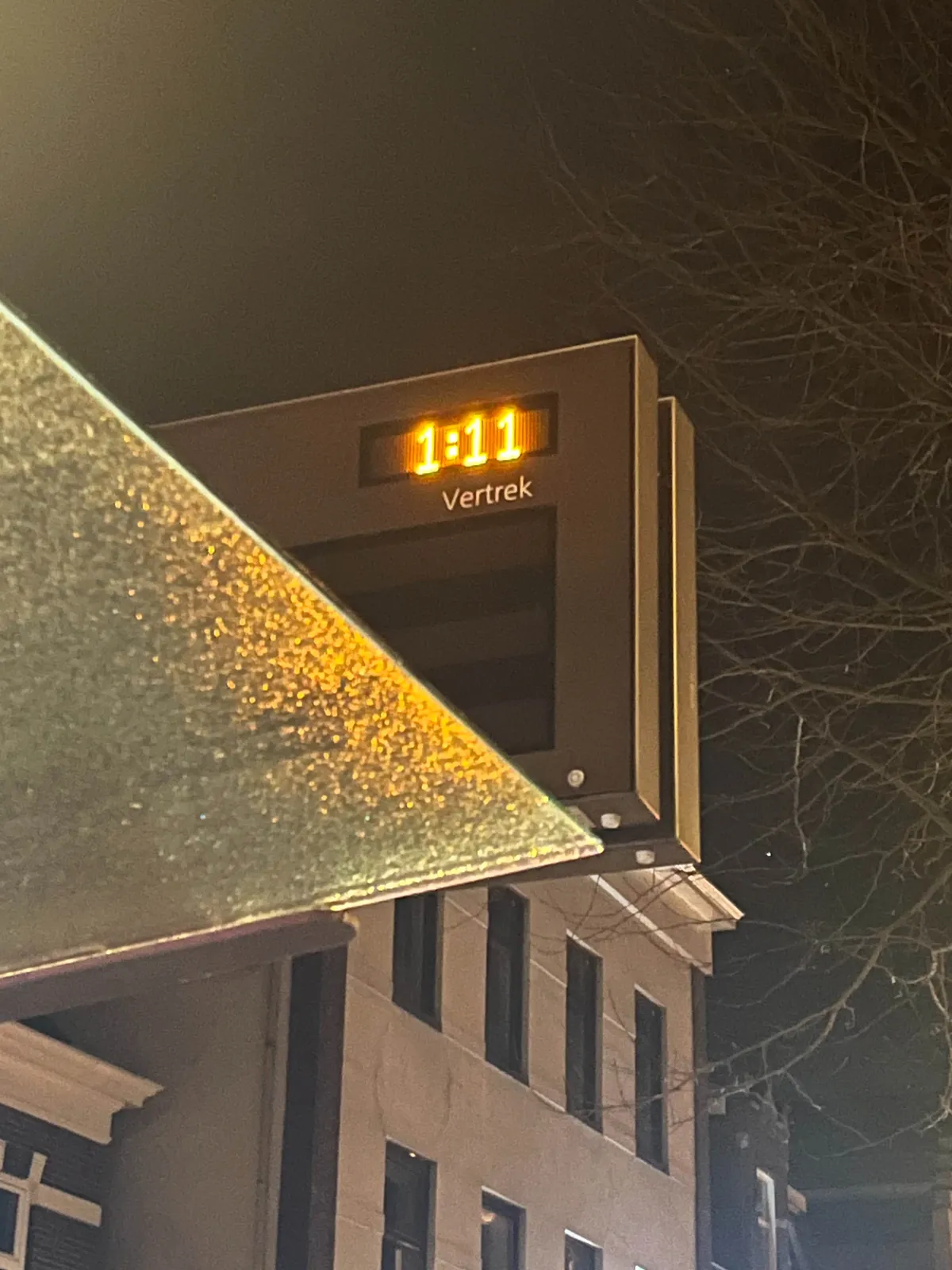 A picture of a public transport display, at night. The time on the display, shown in a brightly lit orange font, is 1:11
