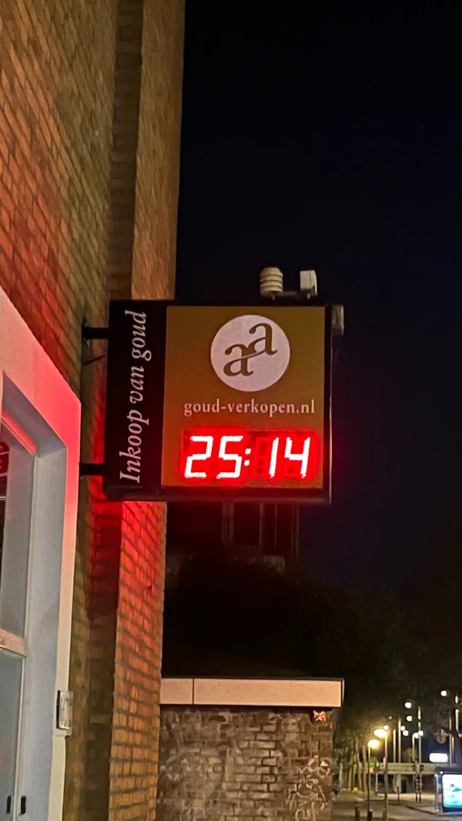 It’s dark outside. A billboard, attached to a brick building, which houses a business that buys and sells gold. There’s a digital clock in this billboard with red, brightly lit numbers. It shows the time in an extraordinary way: it says it is 25:14 which means, I think, 14 minutes past one o’clock in the middle of the night