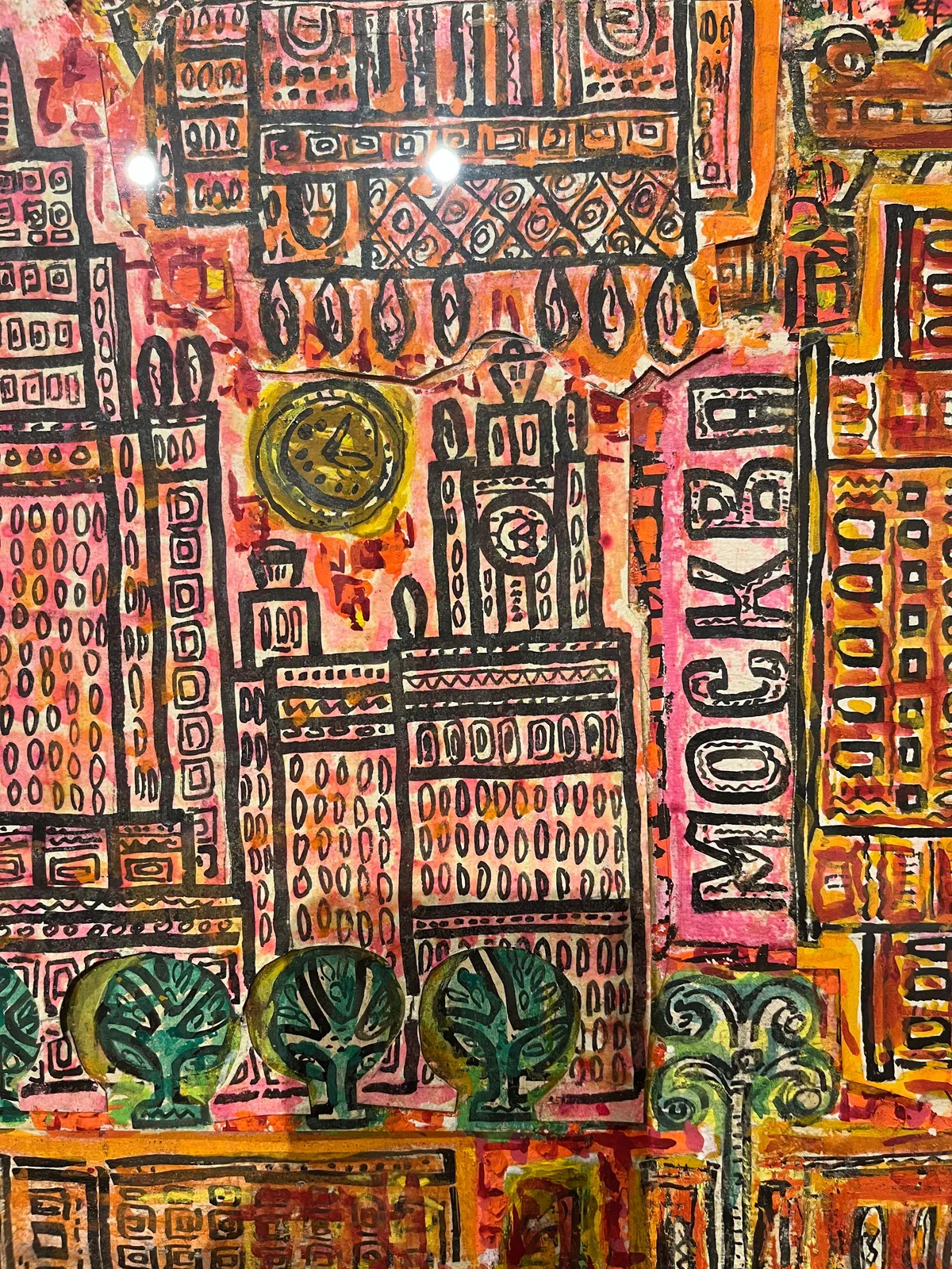 A detail of a colourful, pretty busy painting. It seems like a simplified map of Moscow. There are all kinds of buildings on this painting. On two of these buildings there’s a clock. One of them points at 23 minutes past one. The other points at 5 past 3