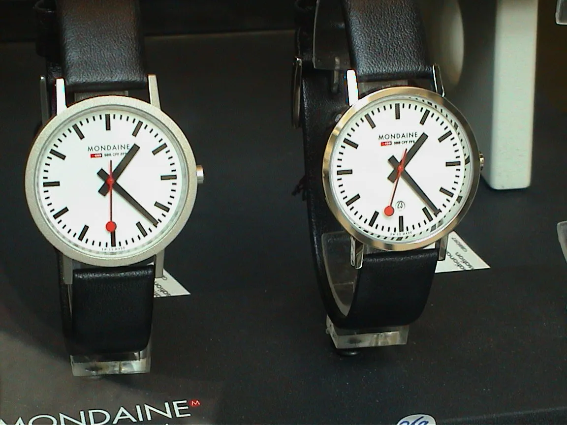 Two watches on display. One points at 23 past one. The other at 24 past one. 