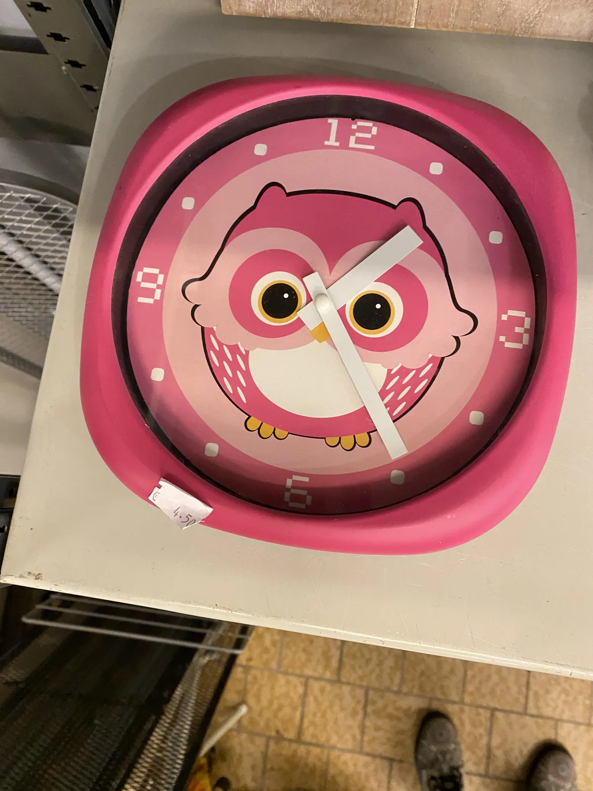 A very pink clock with an owl printed on its face. It points at 24 minutes past one.