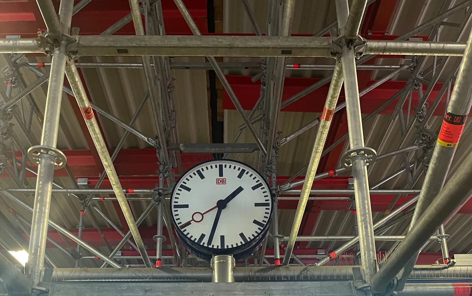 A station clock surrounded by scaffolding. It points at 27 minutes to 2.