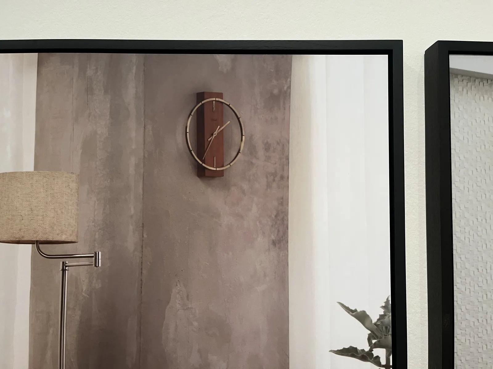 A picture taken from the right top part of a framed picture. In this picture there’s a wall clock which points at 35 minutes past one.