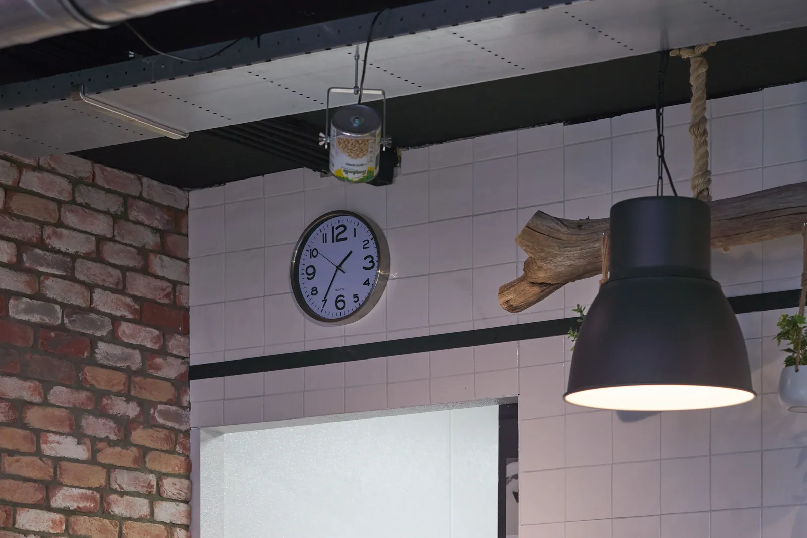 Some details: there’s a log hanging on the wall, there’s an industrial lamp, and there’s a lamp that’s made from a tin can that used to have beans in it. There’s also a clock that points at 35 past one.