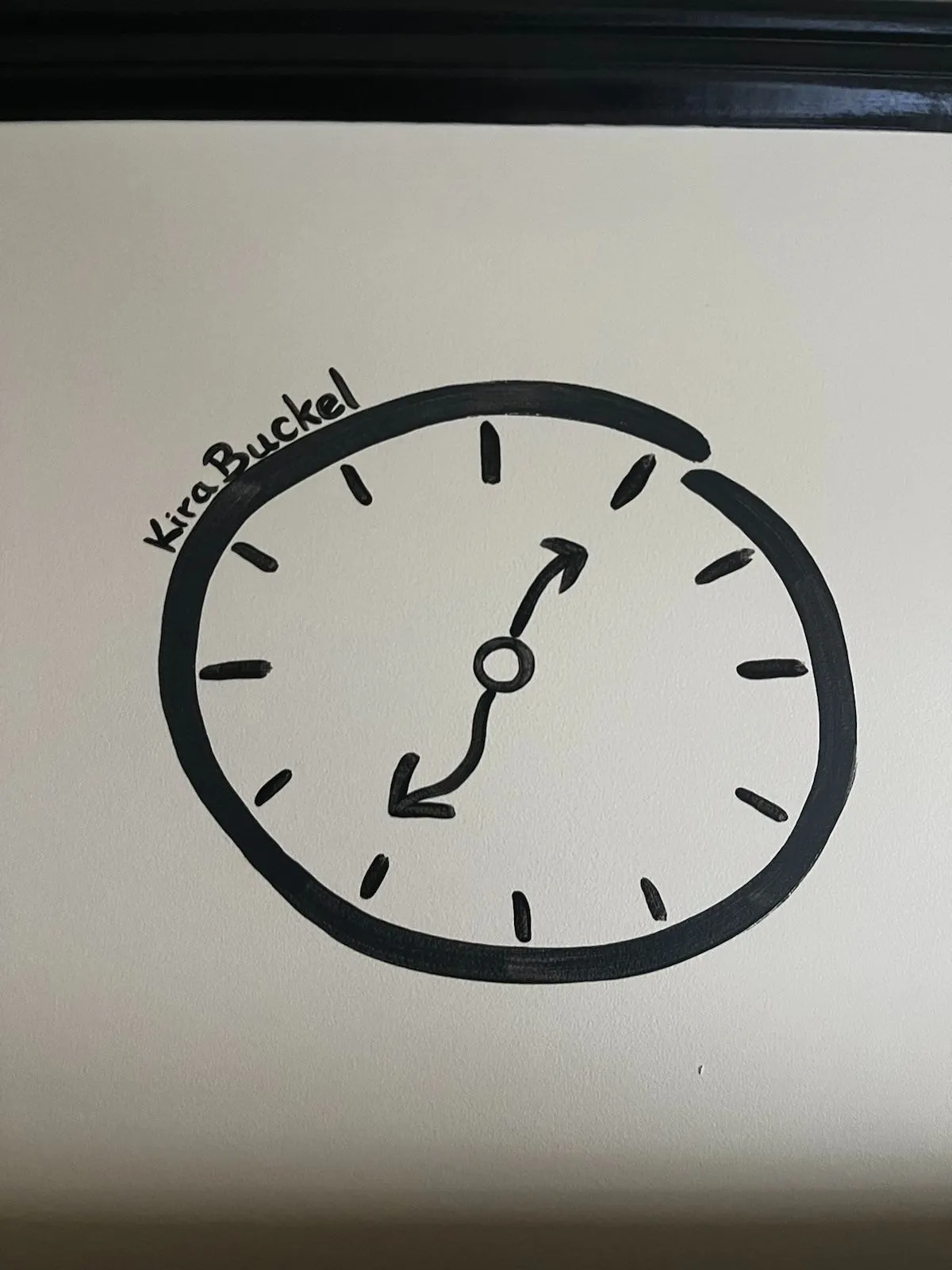A hand drawn clock on a wall, by Kira Buckel, it says. The hands are wavy so it’s hard to tell the time, but it could very well be that the clock points at approximately 24 minutes to 2.