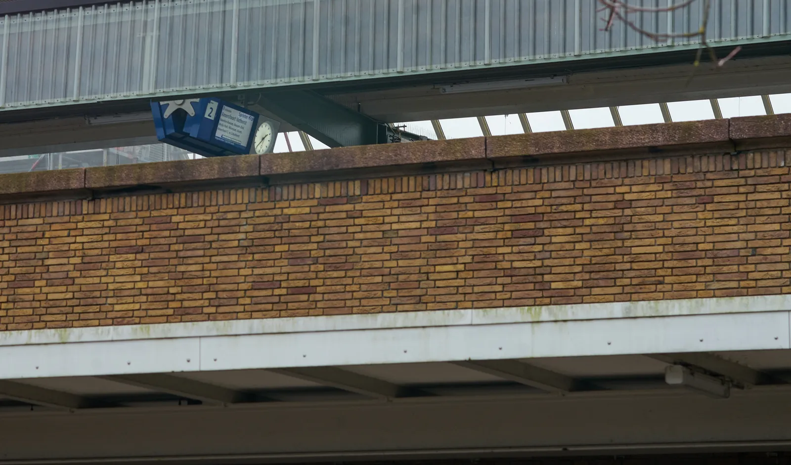 Peeking through a gap you can see a clock on a train platform. It says it is 37 past one.