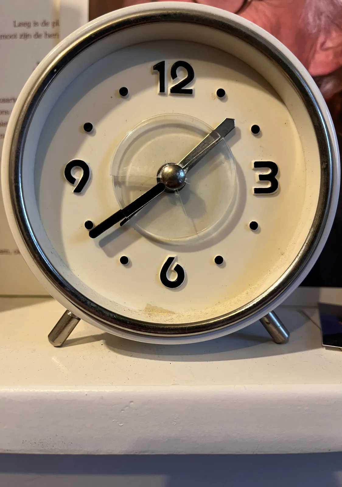 A small clock with very clear features. It doesn’t have a glass protective plate, since it is designed for blind people so they can feel the time. It points at 21 minutes to 2.