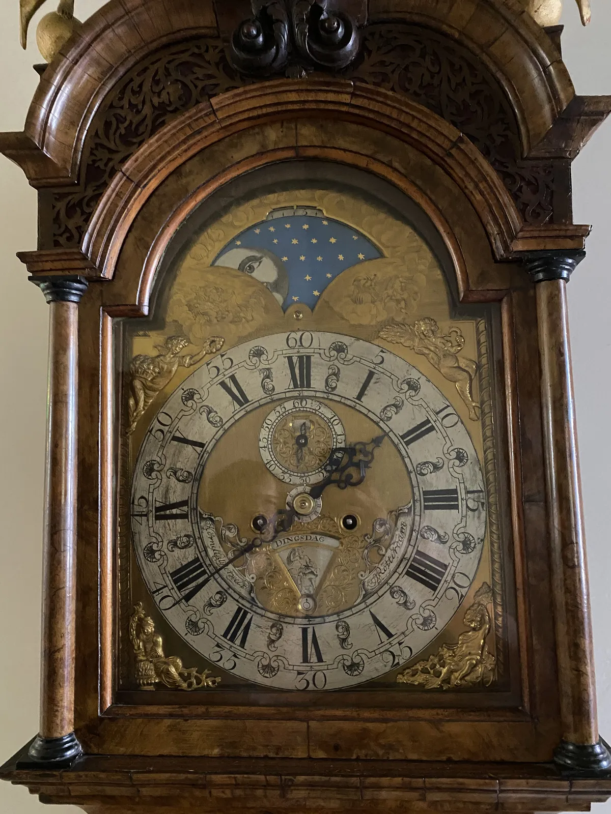 An old clock, with angels embossed in its metal face plate. It has a day and night indicator which isn’t very clear about what it is right now. The clock points at 39 past 1.