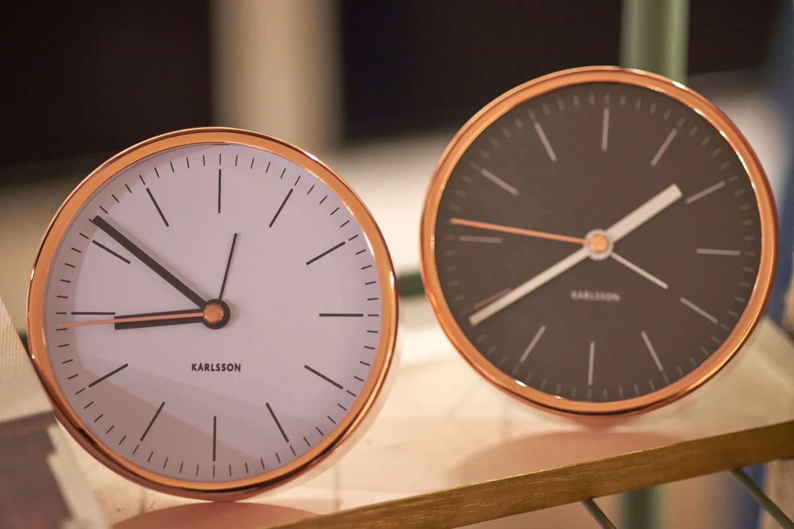 There are two clocks on this picture. The one on the left is white, the one on the right is black. The one on the left points at nine minutes to nine. The one on the right points at 21 minutes to 2.
