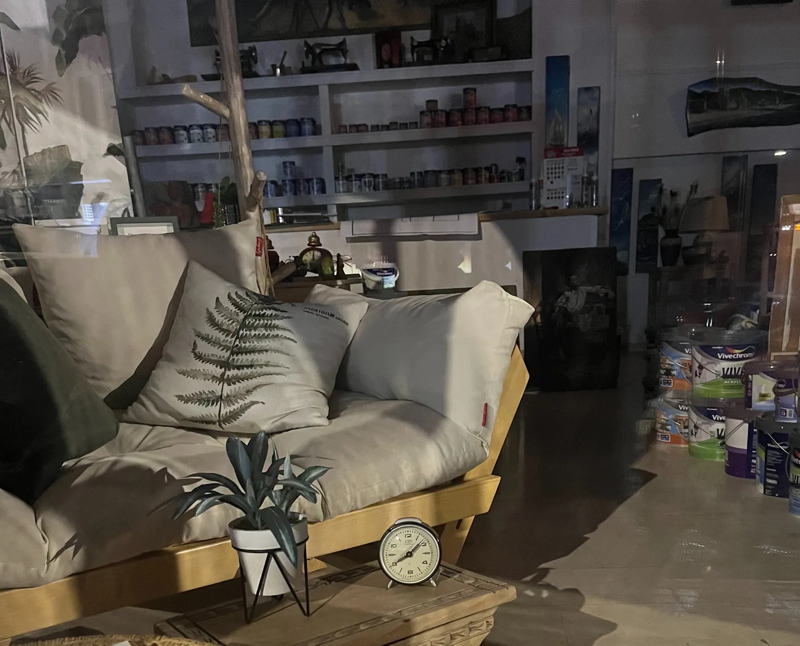 Inside a decoration shop there’s a clock on a side table, in front of a couch. The clock points at 20 to 2