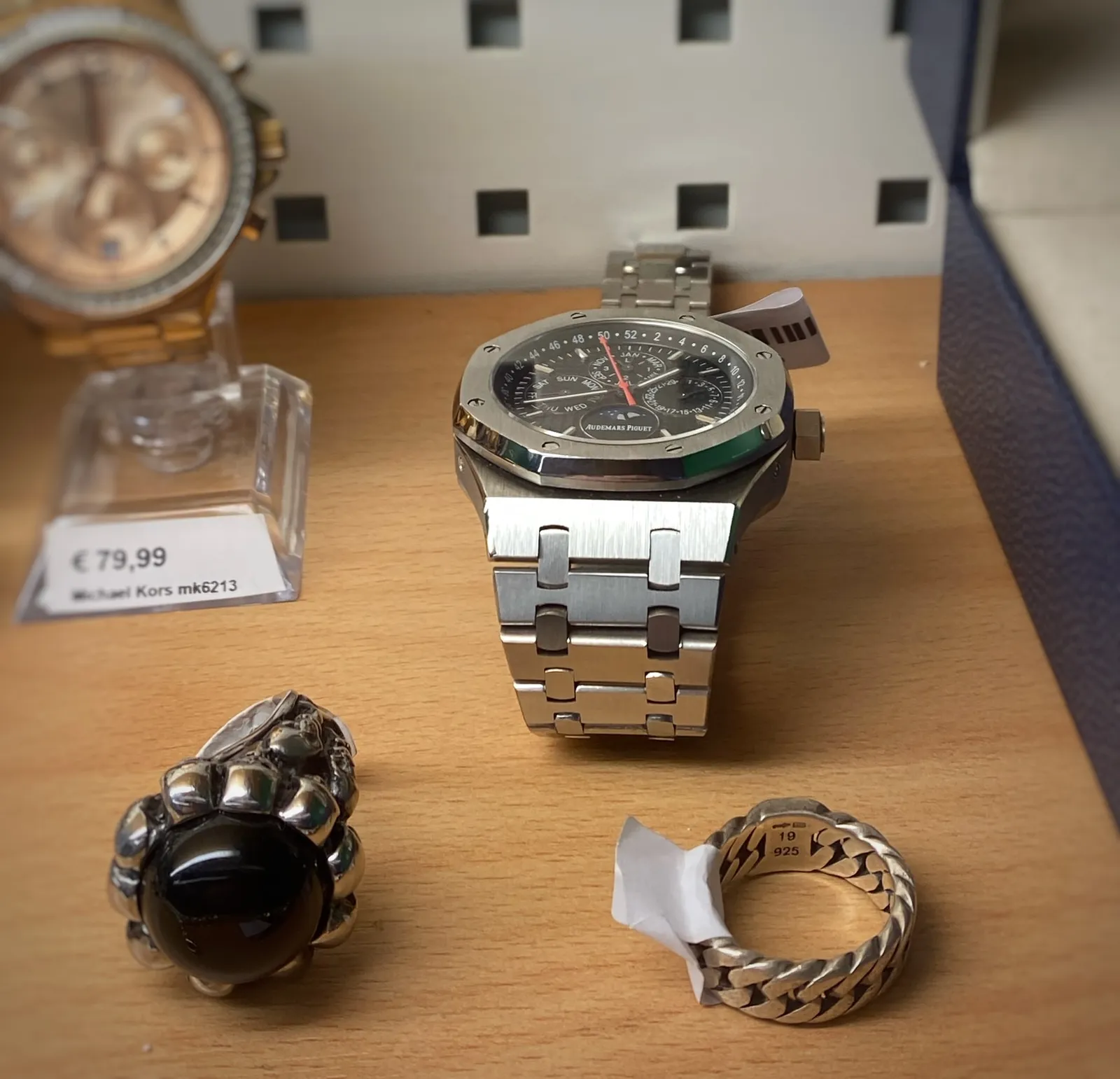 Two rings and two watches for sale. Only one of these watches is in focus. The time on this watch is 18 minutes to 2.